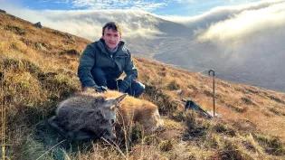 Person on a mountain with a dead deer