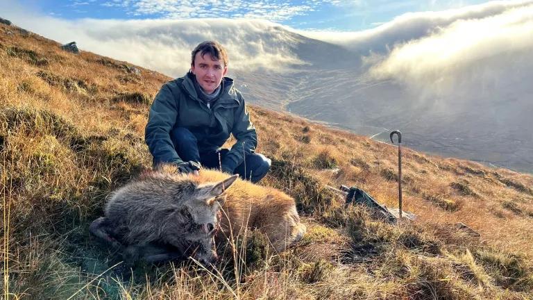 Person on a mountain with a dead deer