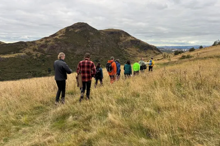 group of people walking over a hill
